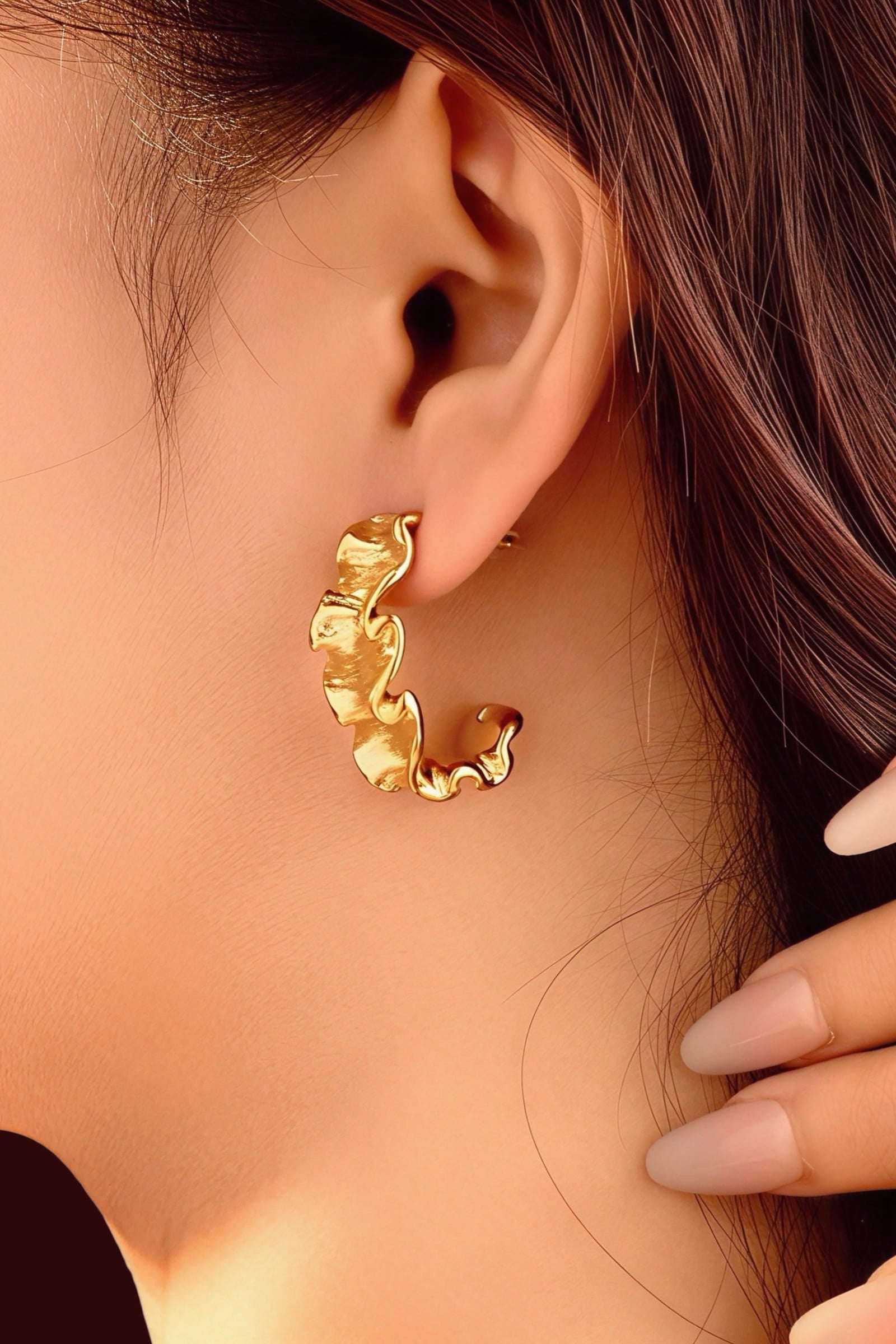 Close-up of textured wave C-hoop earrings crafted from stainless steel with a radiant PVD 18K gold plated finish, featuring sculpted wave-like curves and a modern statement design – GLISTIA.