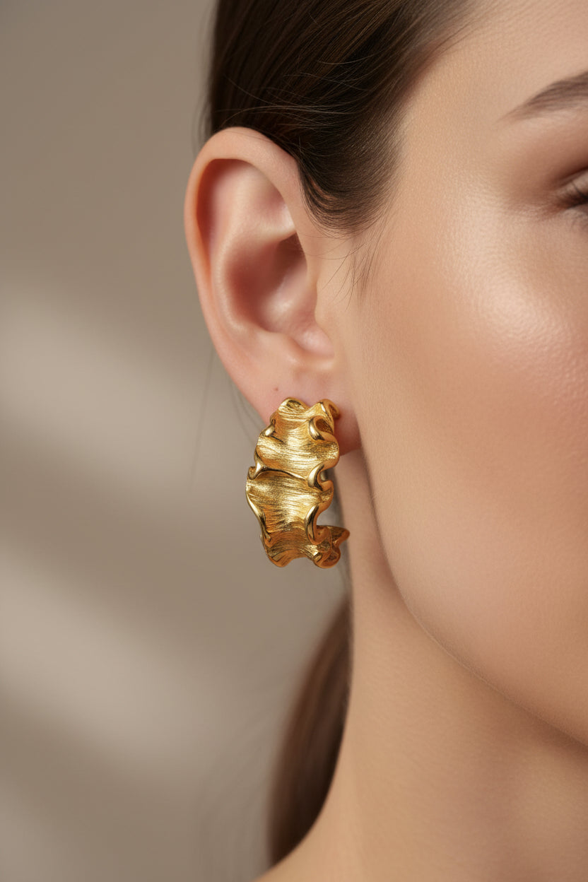 Close-up of textured wave hoop earrings in 18K PVD gold plated stainless steel, showcasing sculptural wave detailing and a matte-polished finish
