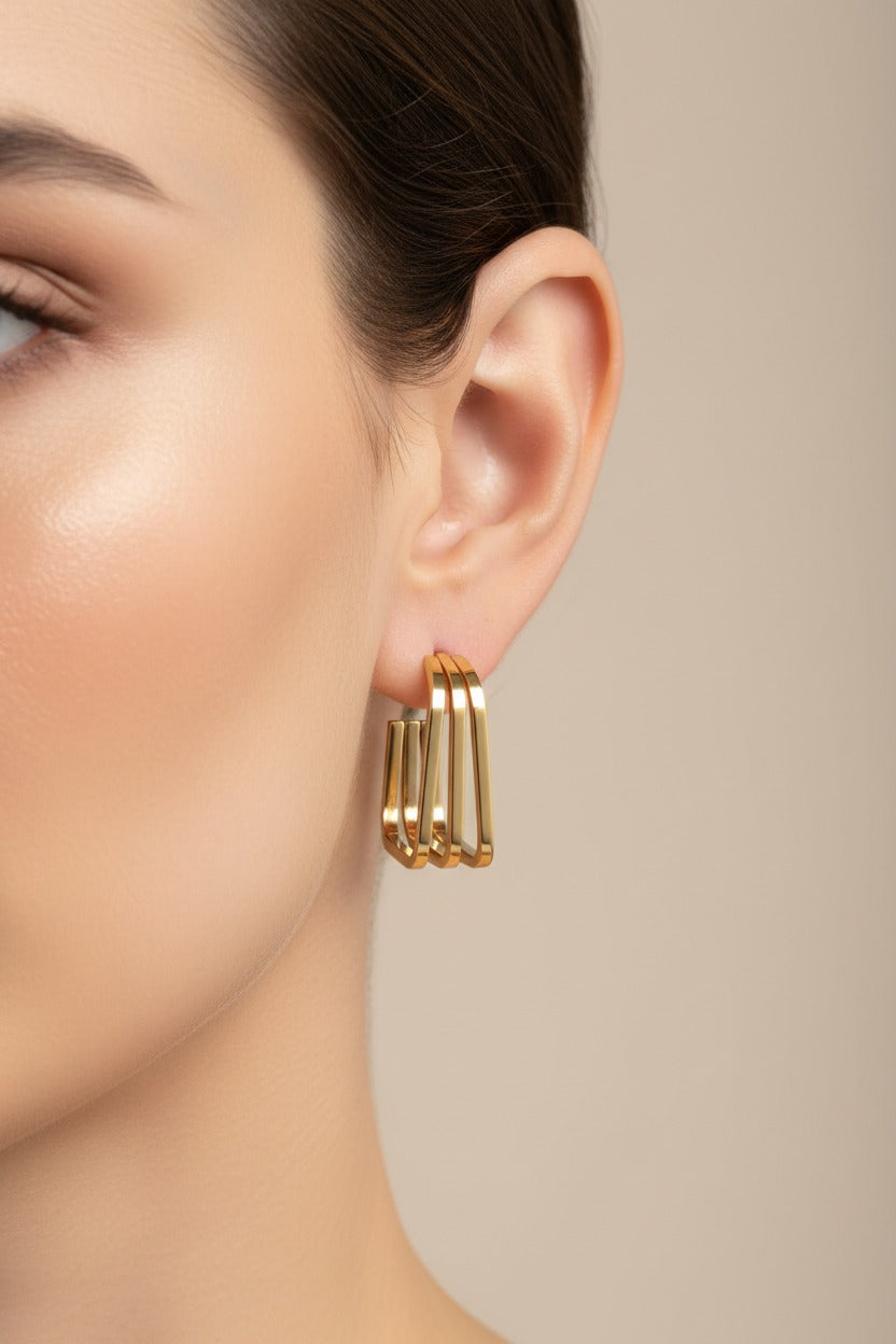 Triple-layer square hoop earrings in 18K PVD gold plated stainless steel worn on ear, modern geometric gold hoops
