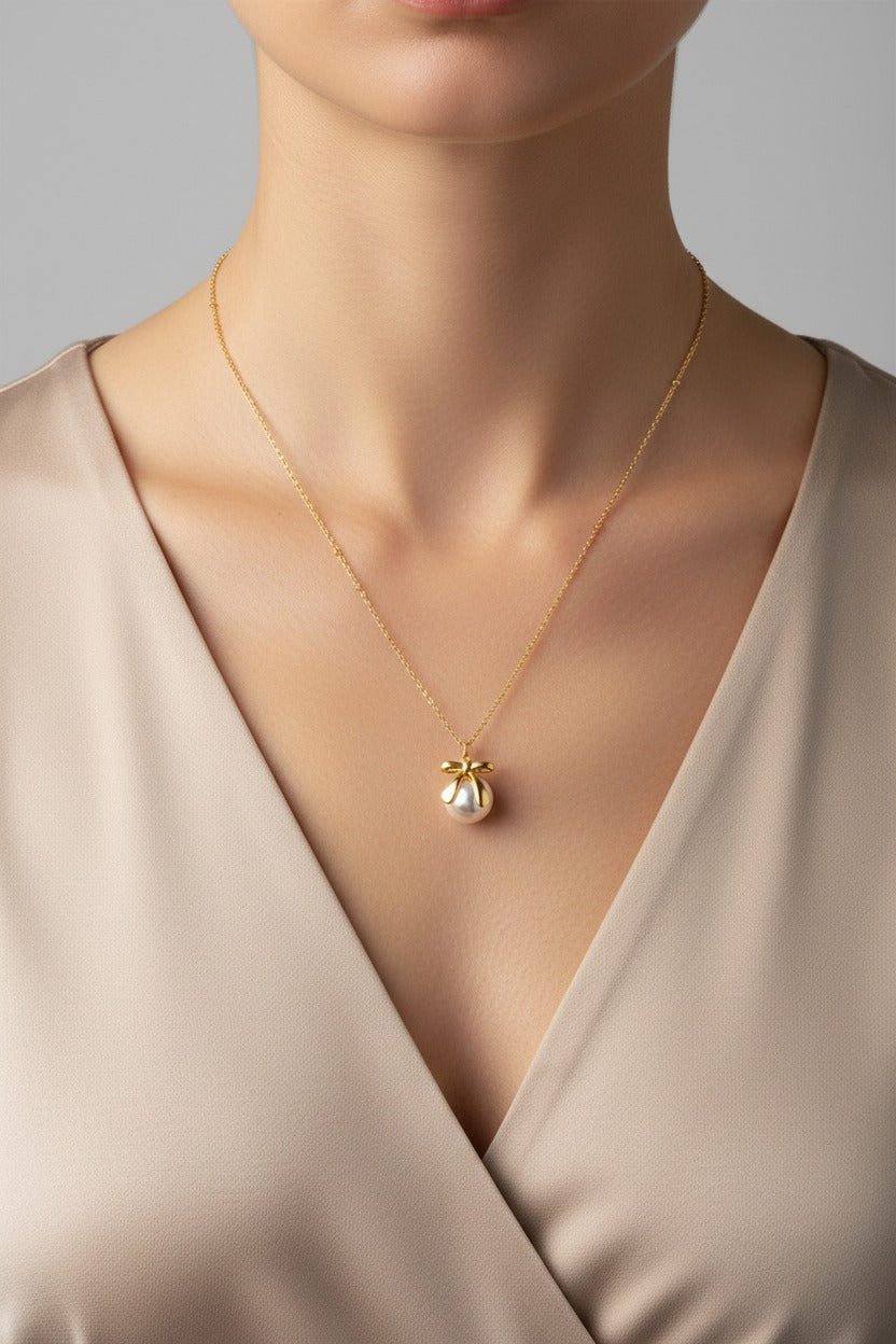 Aurelia bow pearl pendant necklace in 18K PVD gold plated stainless steel with delicate bow design and pearl drop