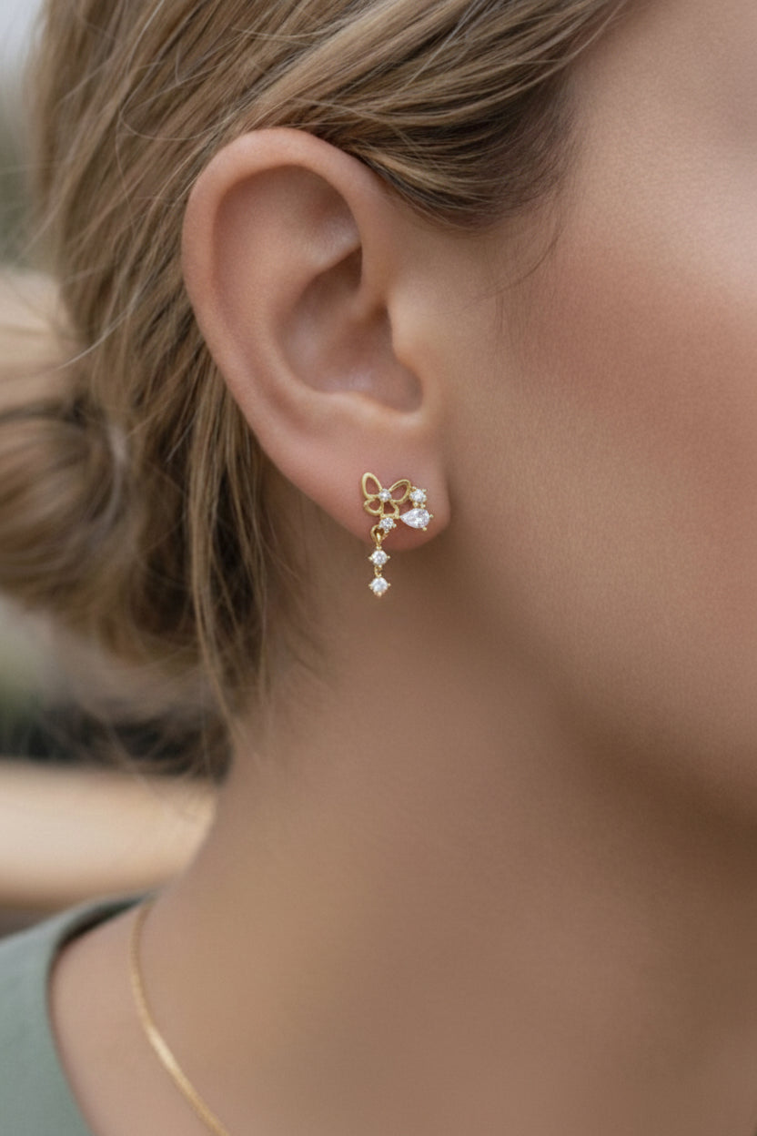 Butterfly drop piercing earrings in 18K PVD gold plating with cubic zirconia stones, worn on ear cartilage