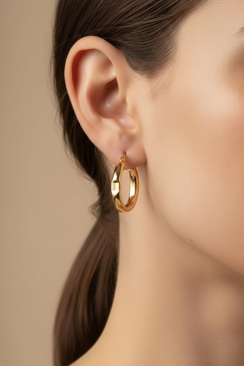Close-up of chunky hoop earrings in 18K PVD gold plated stainless steel, showcasing a polished surface and modern minimalist profile