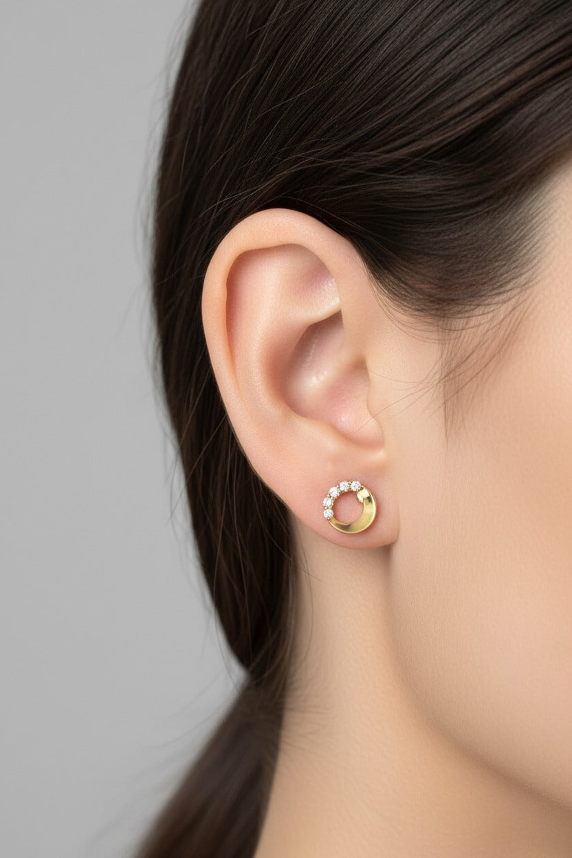 Crescent crystal moon stud earrings in 18K PVD gold plated stainless steel with clear crystals, worn on ear for lobe or cartilage piercing