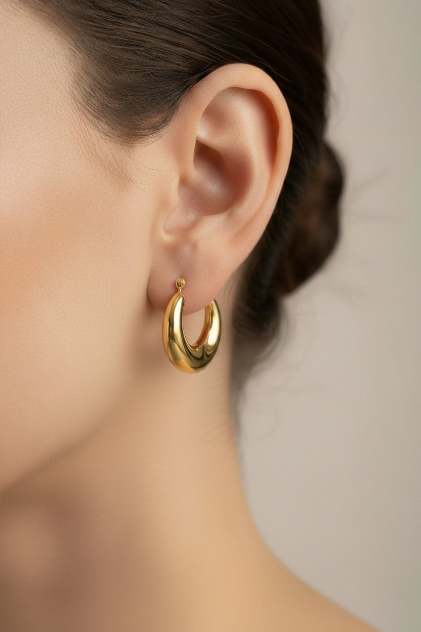 18K PVD gold plated crescent hoop earrings on model ear with polished curved silhouette