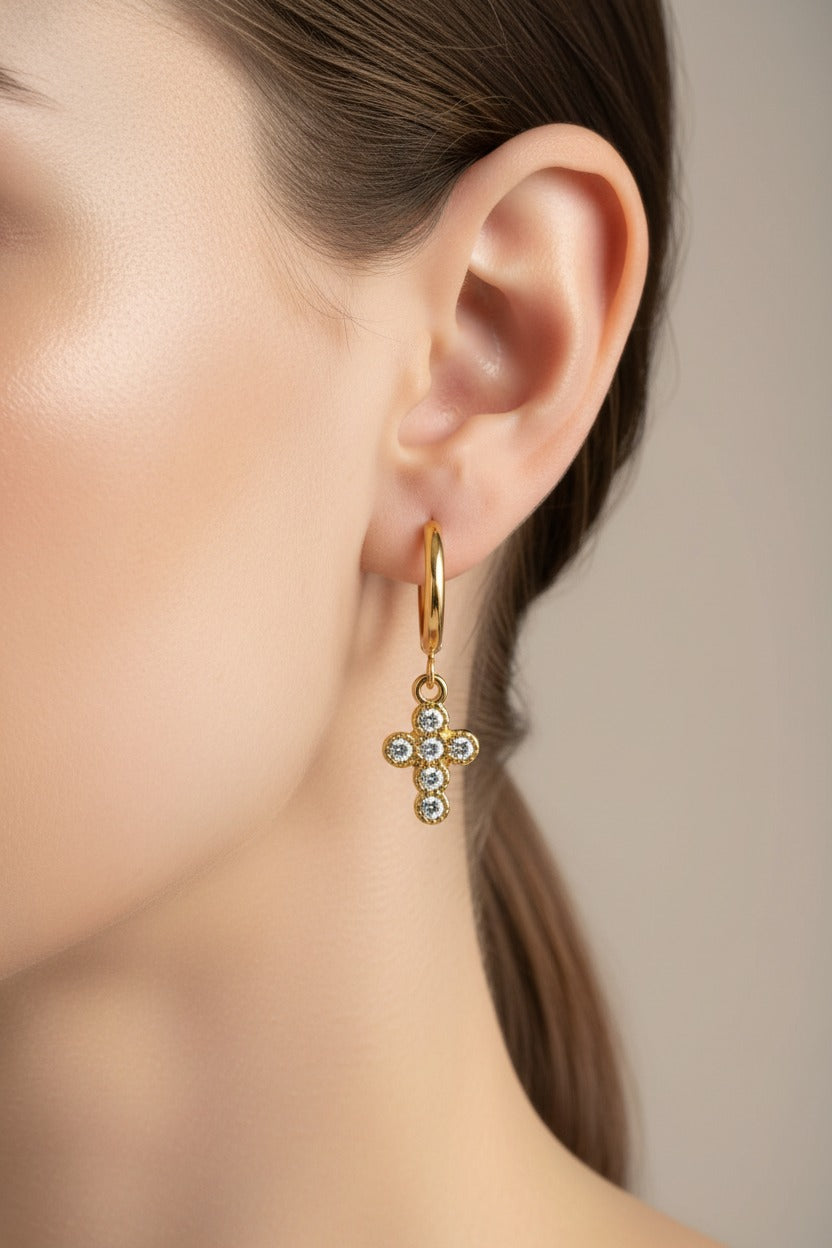 Crystal cross charm hoop earrings worn on ear, crafted from stainless steel with 18K PVD gold plating and sparkling crystal details
