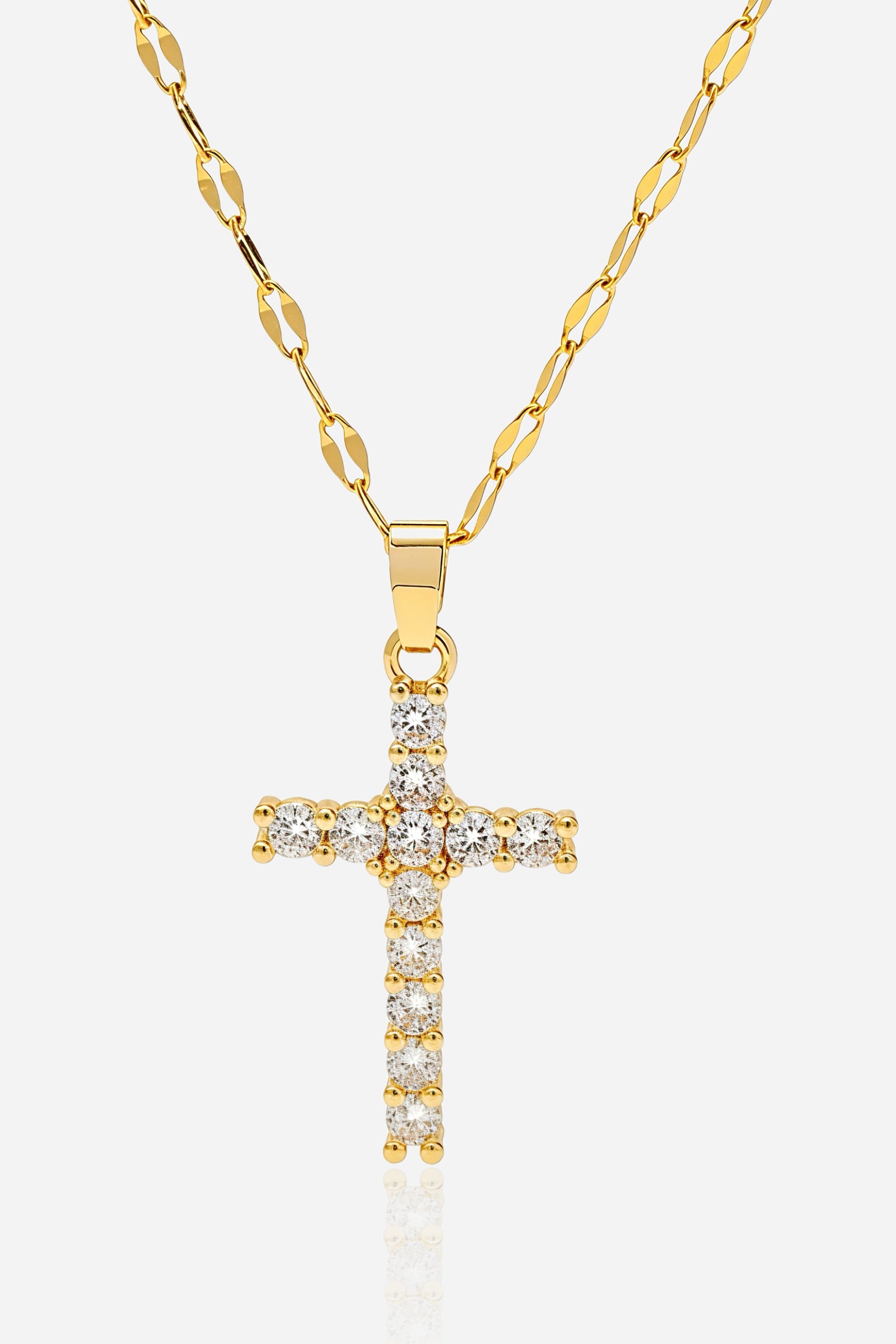 Close-up shot of GLISTIA 18K gold PVD cross pendant with clear zircon baguettes.