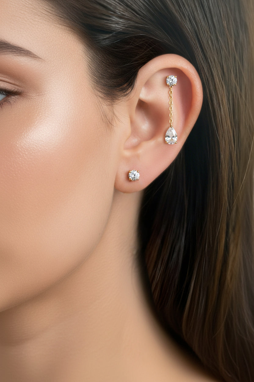 Dangle crystal chain stud earring crafted from stainless steel with 18K PVD gold plating, featuring round and teardrop cubic zirconia crystals linked by a fine chain