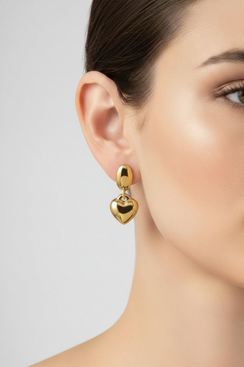 Dangle heart earrings crafted from stainless steel with 18K PVD gold plating, featuring a polished oval stud and smooth heart drop.