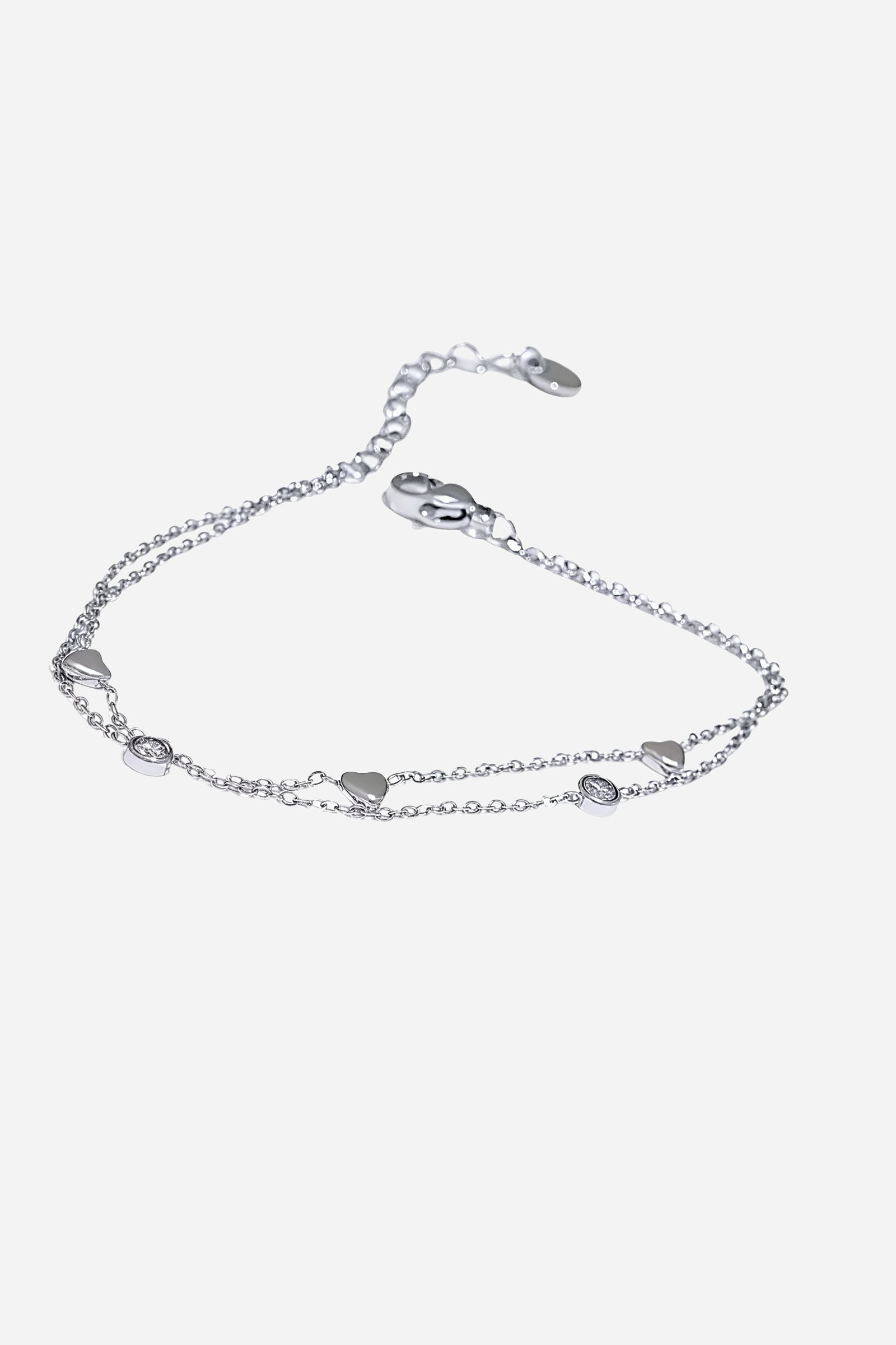 Top-view of GLISTIA’s delicate dual chain bracelet featuring mini heart charms and bezel-set crystal accents.