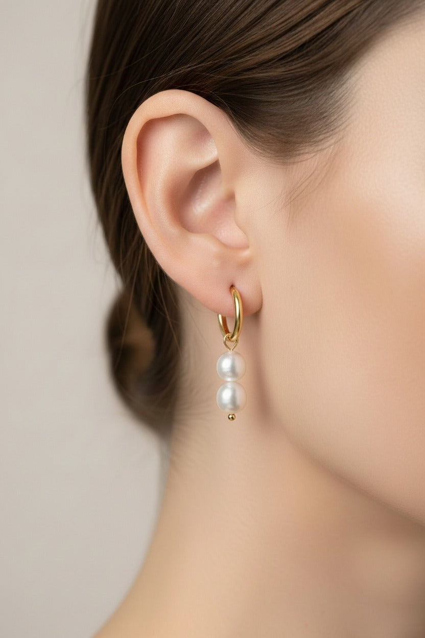 Double pearl drop huggie earrings crafted from stainless steel with 18K PVD gold plating, featuring two lustrous pearl drops suspended from polished hoops.