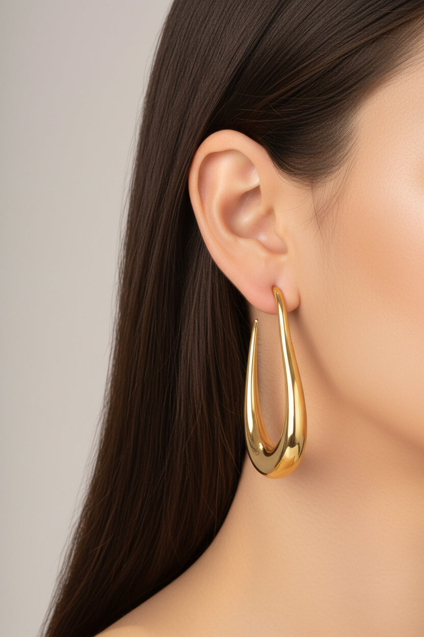 Side view of elongated sculptural hoop earrings in 18K PVD gold plated stainless steel with fluid curved design
