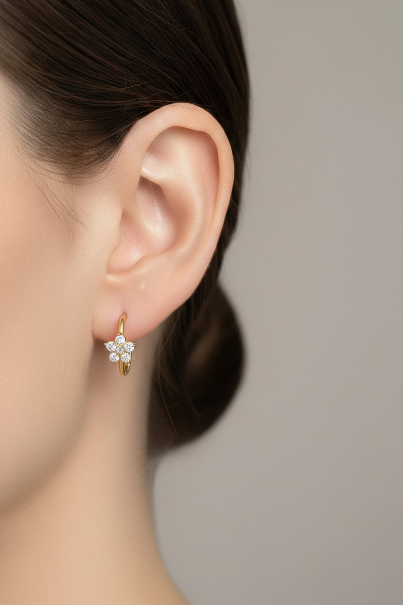Close-up of hoop earrings with flower-shaped zirconia detail in 18K PVD gold plated stainless steel, showcasing brilliant white zirconia stones