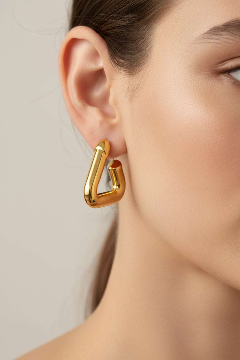 Close-up of geometric triangle hoop earrings in 18K PVD gold plated stainless steel, showcasing a sculptural modern design and clean angular lines