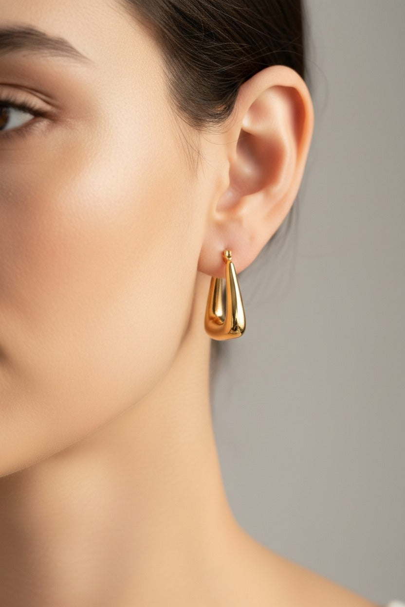 Geometric triangle hoop earrings in 18K PVD gold plated stainless steel worn on model ear, GLISTIA everyday gold jewellery