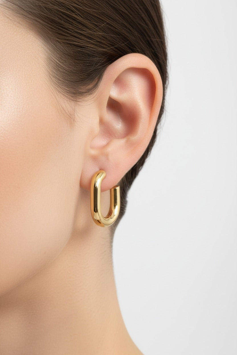 GLISTIA Elara gold hoop earrings in 18K PVD gold plating, worn on ear, polished C-curve stainless steel design