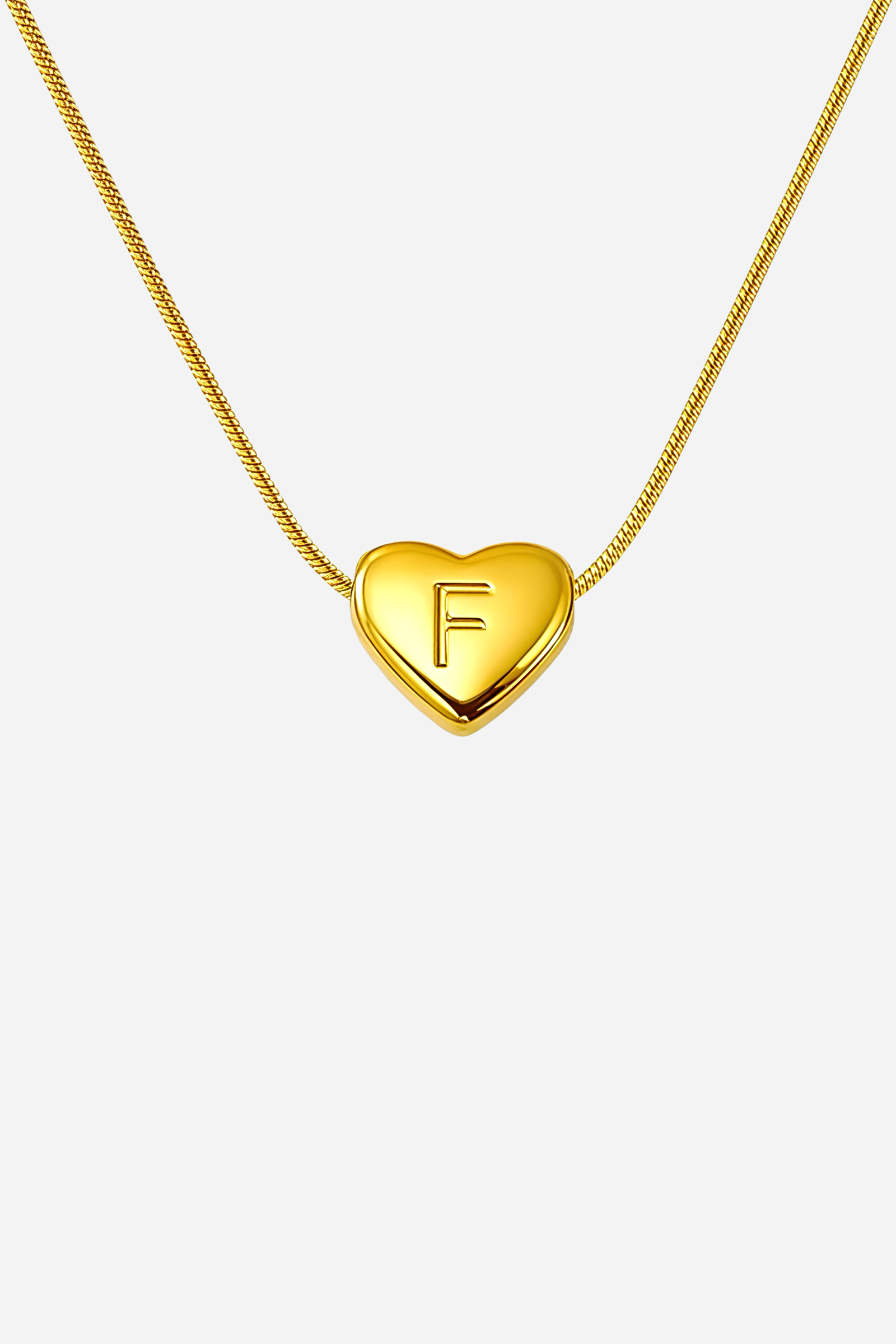 Close-up of heart initial ‘F’ pendant showcasing engraved lettering and mirror-polished gold plating – GLISTIA