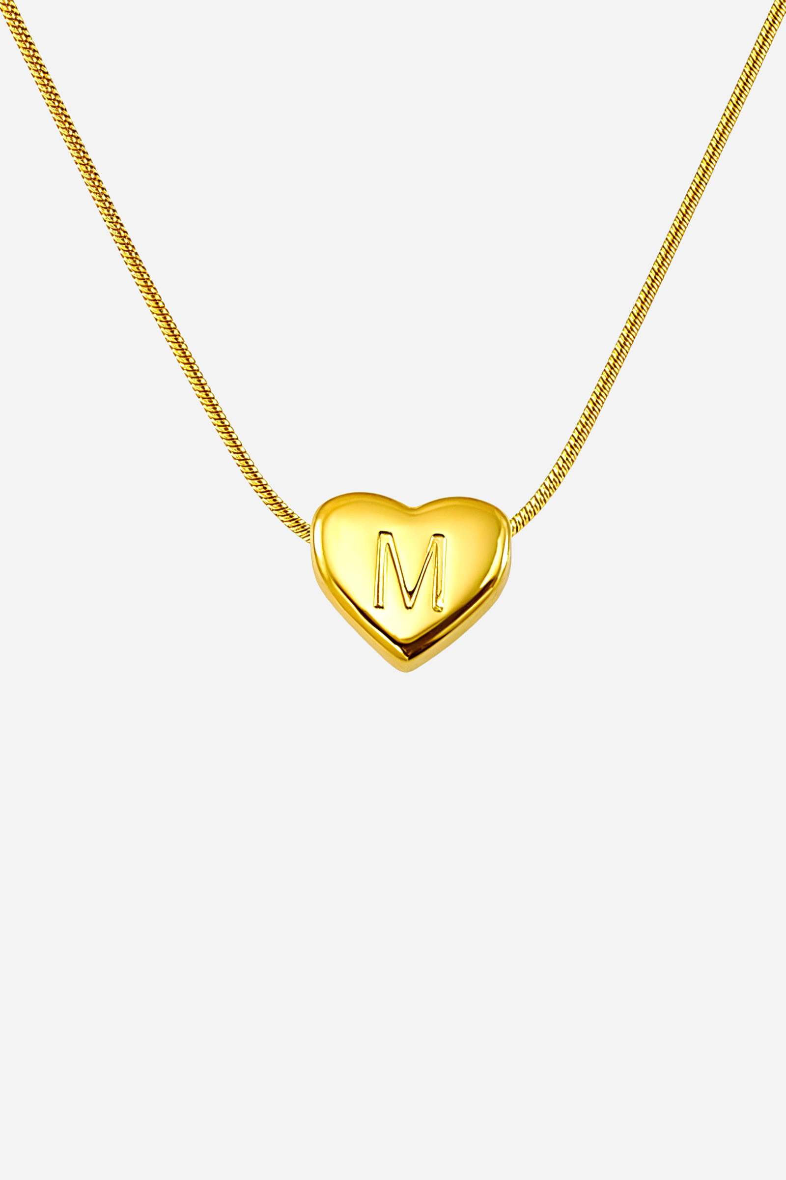 Close-up of heart-shaped initial ‘M’ pendant highlighting engraved letter and mirror-polished gold finish – GLISTIA