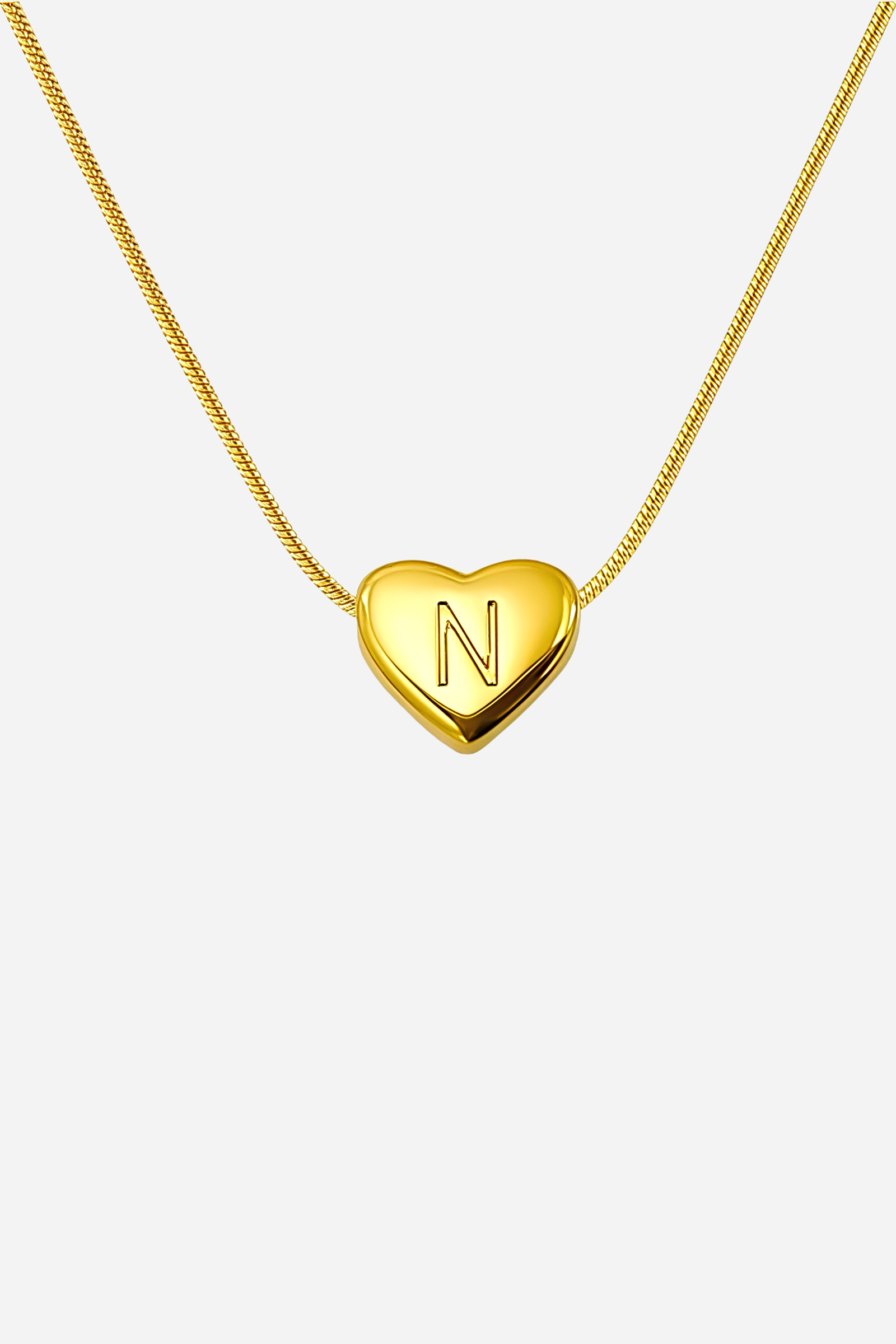 Close-up of heart-shaped initial ‘N’ pendant highlighting engraved letter and mirror-polished gold finish – GLISTIA