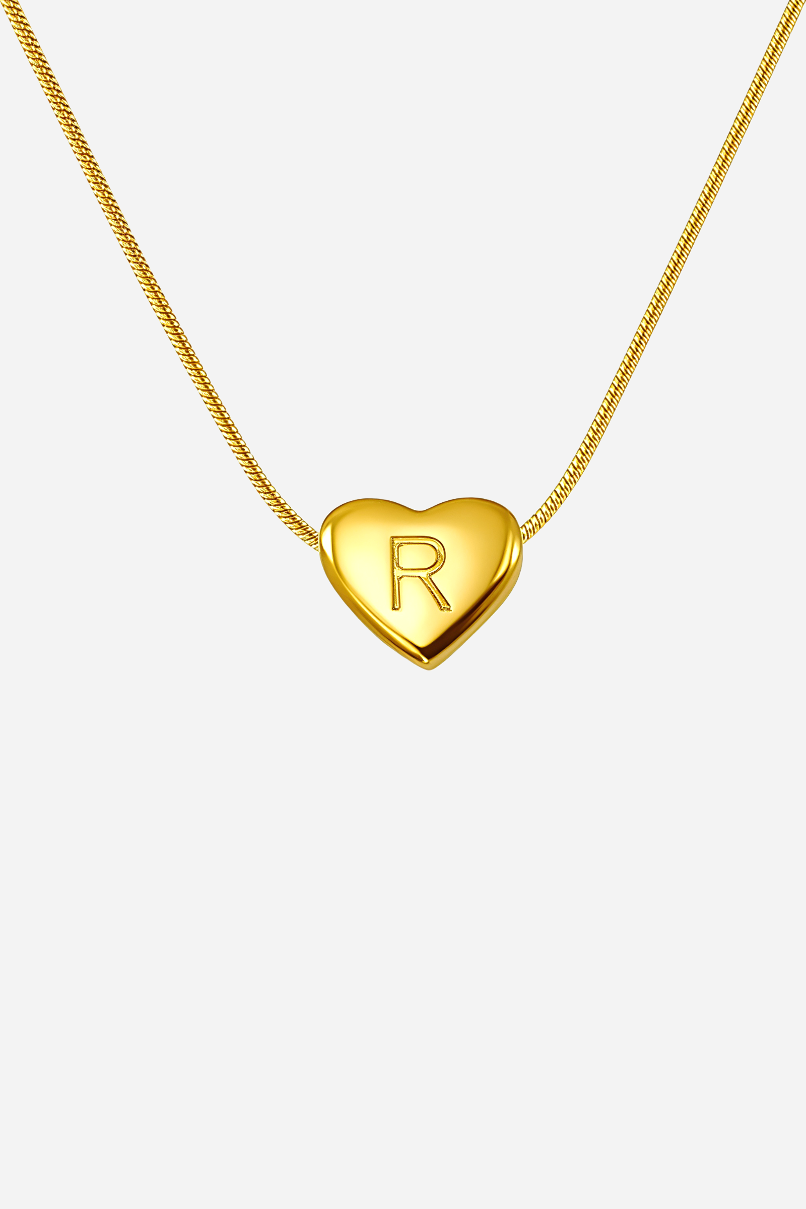 Close-up of heart-shaped initial ‘R’ pendant highlighting engraved letter and mirror-polished gold finish – GLISTIA