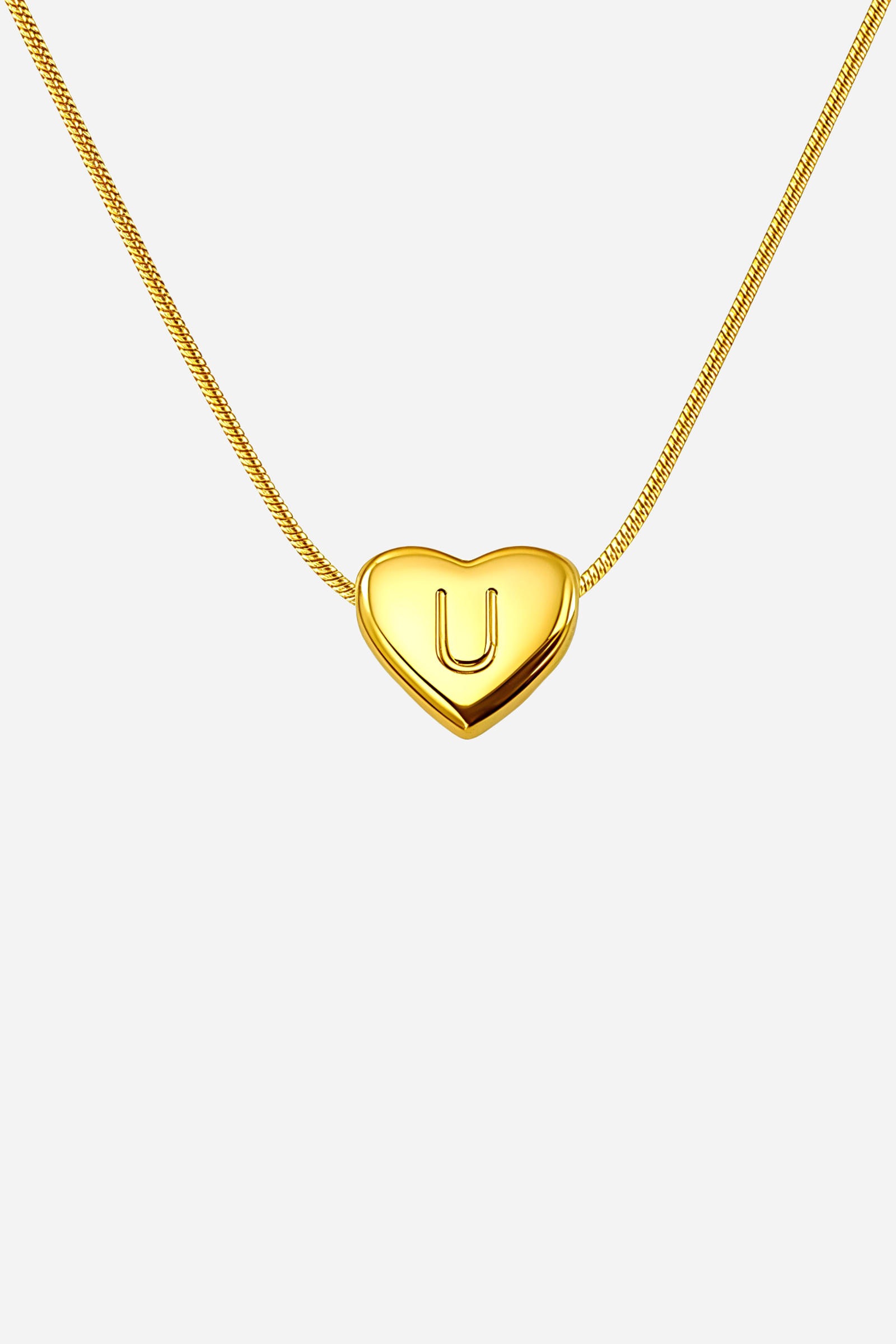 Close-up of heart-shaped initial ‘U’ pendant highlighting engraved letter and mirror-polished gold finish – GLISTIA