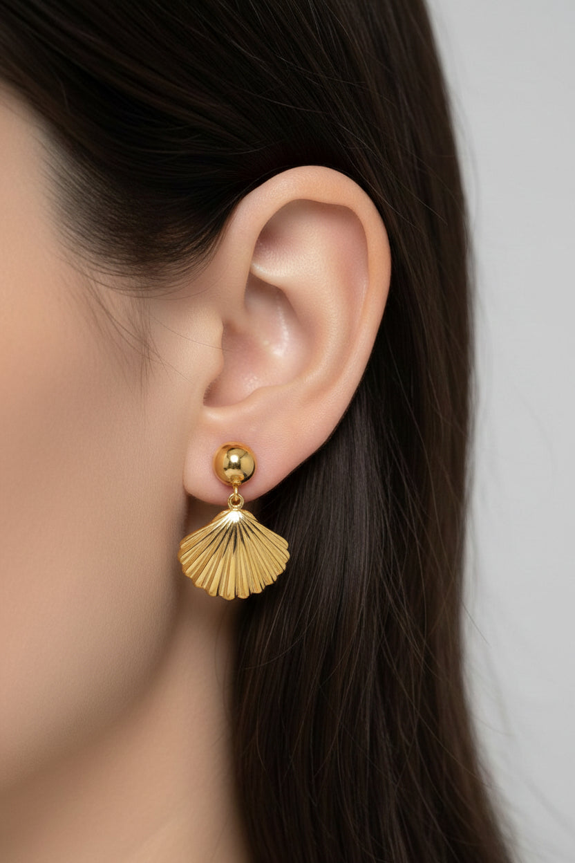 Close-up of seashell drop earrings showcasing fine shell detailing and polished 18K PVD gold plating.