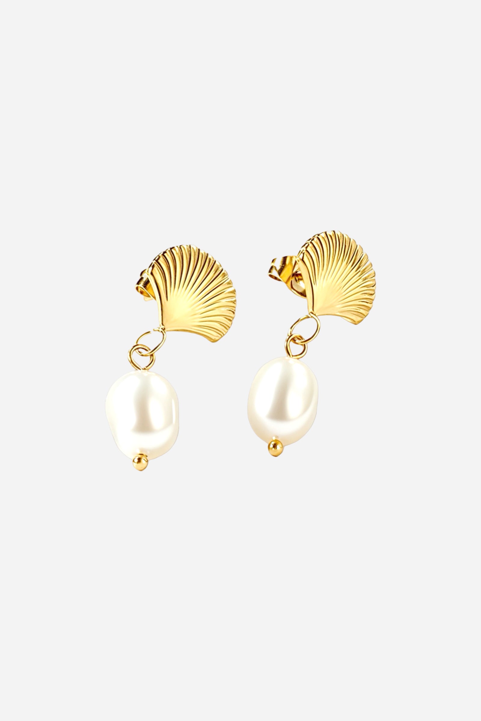 Angled view of gold shell pearl drop earrings crafted from PVD 18K gold plated stainless steel, featuring sculpted fan shell tops and lustrous white pearl drops – GLISTIA.