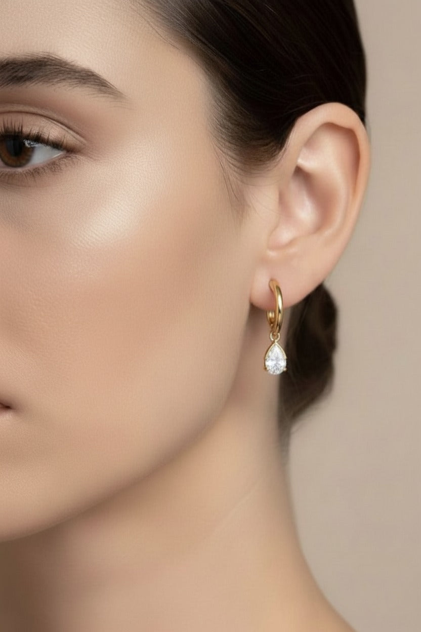 Left ear view of gold teardrop crystal drop hoop earring in 18K PVD gold plated stainless steel