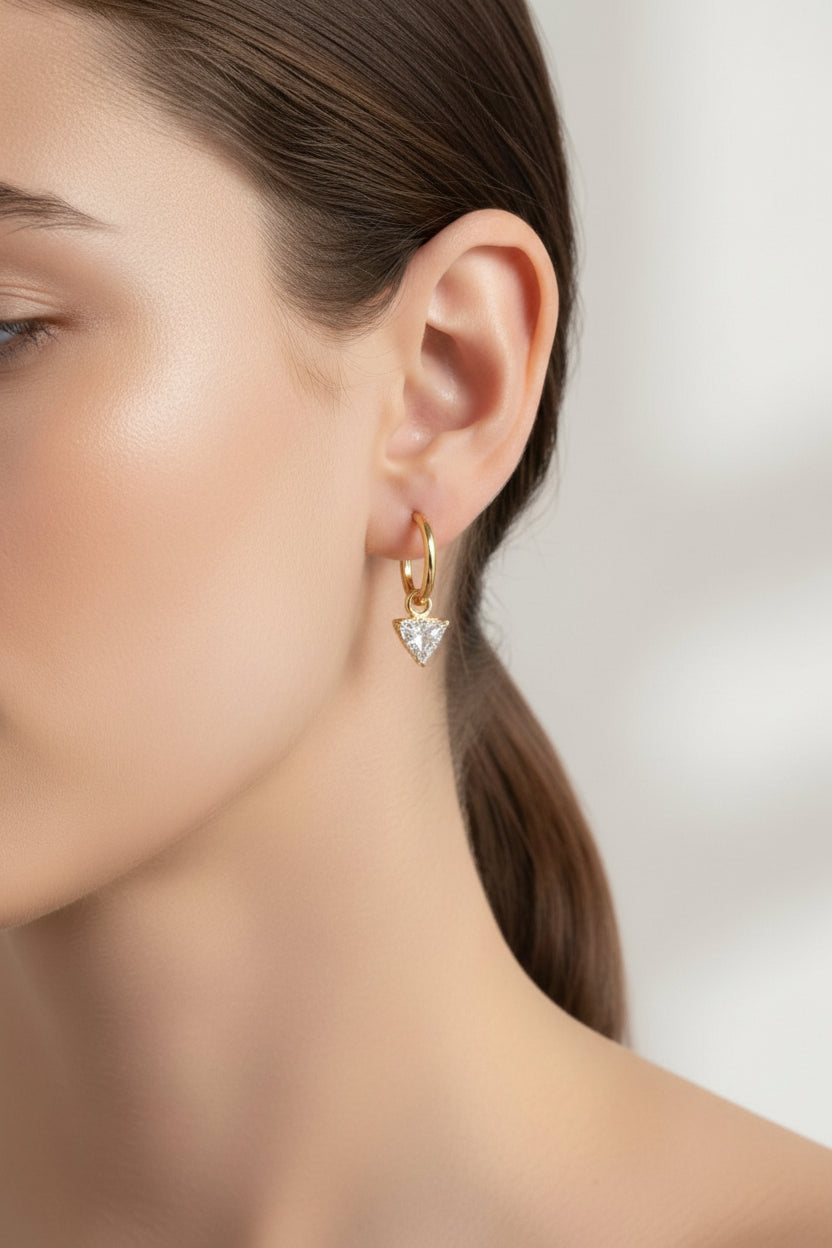 Close-up of hoop earrings with triangle crystal drop in 18K PVD gold plated stainless steel, showcasing a clear geometric crystal charm and elegant minimalist design