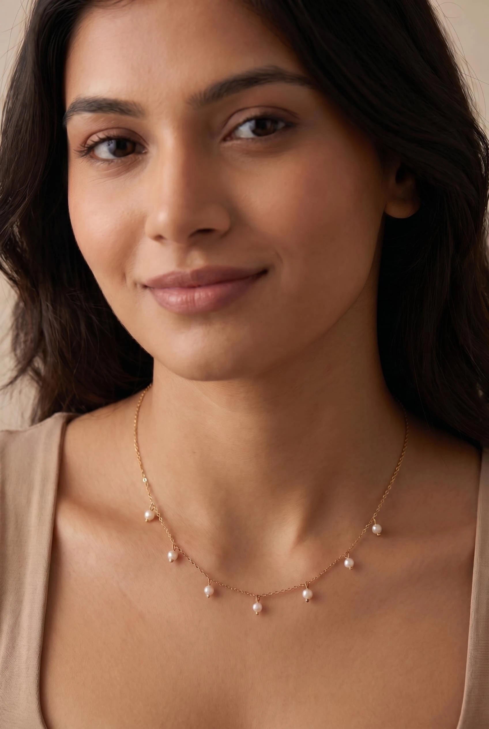 Delicate gold pearl drop necklace featuring small white pearls on a fine chain, designed for refined everyday styling by GLISTIA.