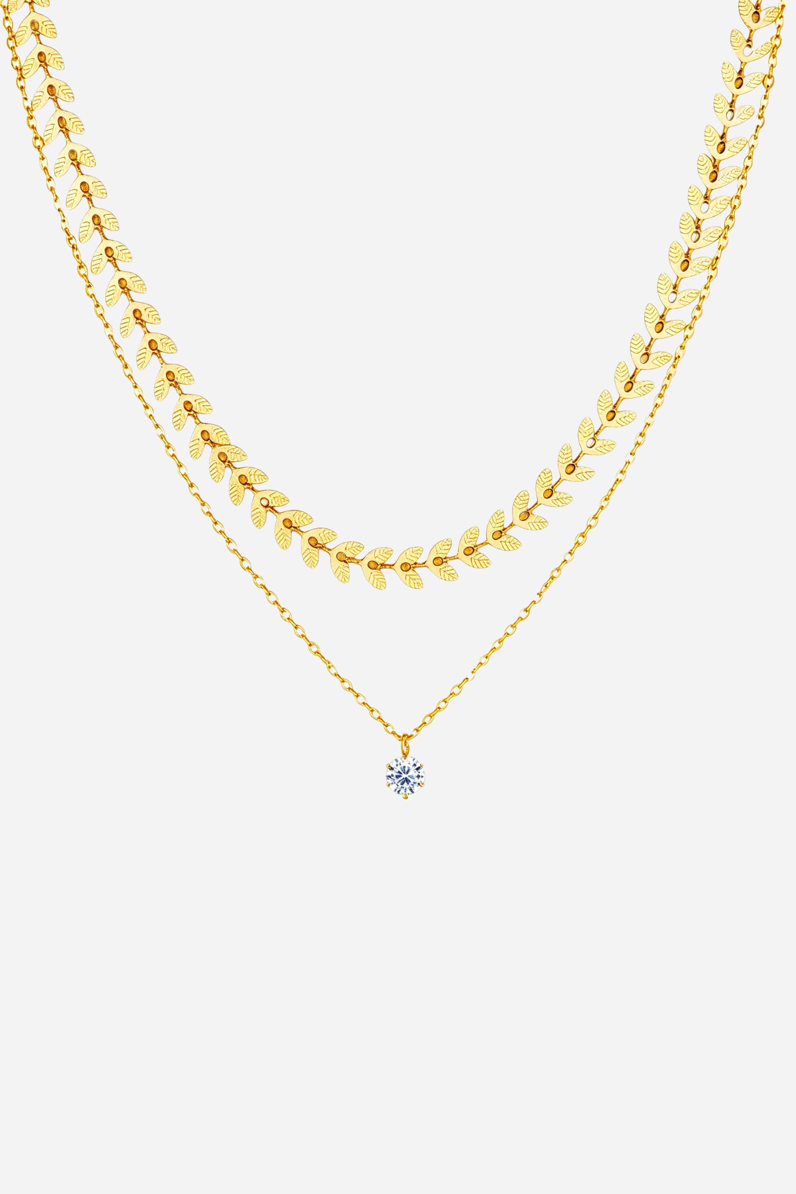 Top-view image of GLISTIA layered necklace featuring gold laurel chain and crystal charm.