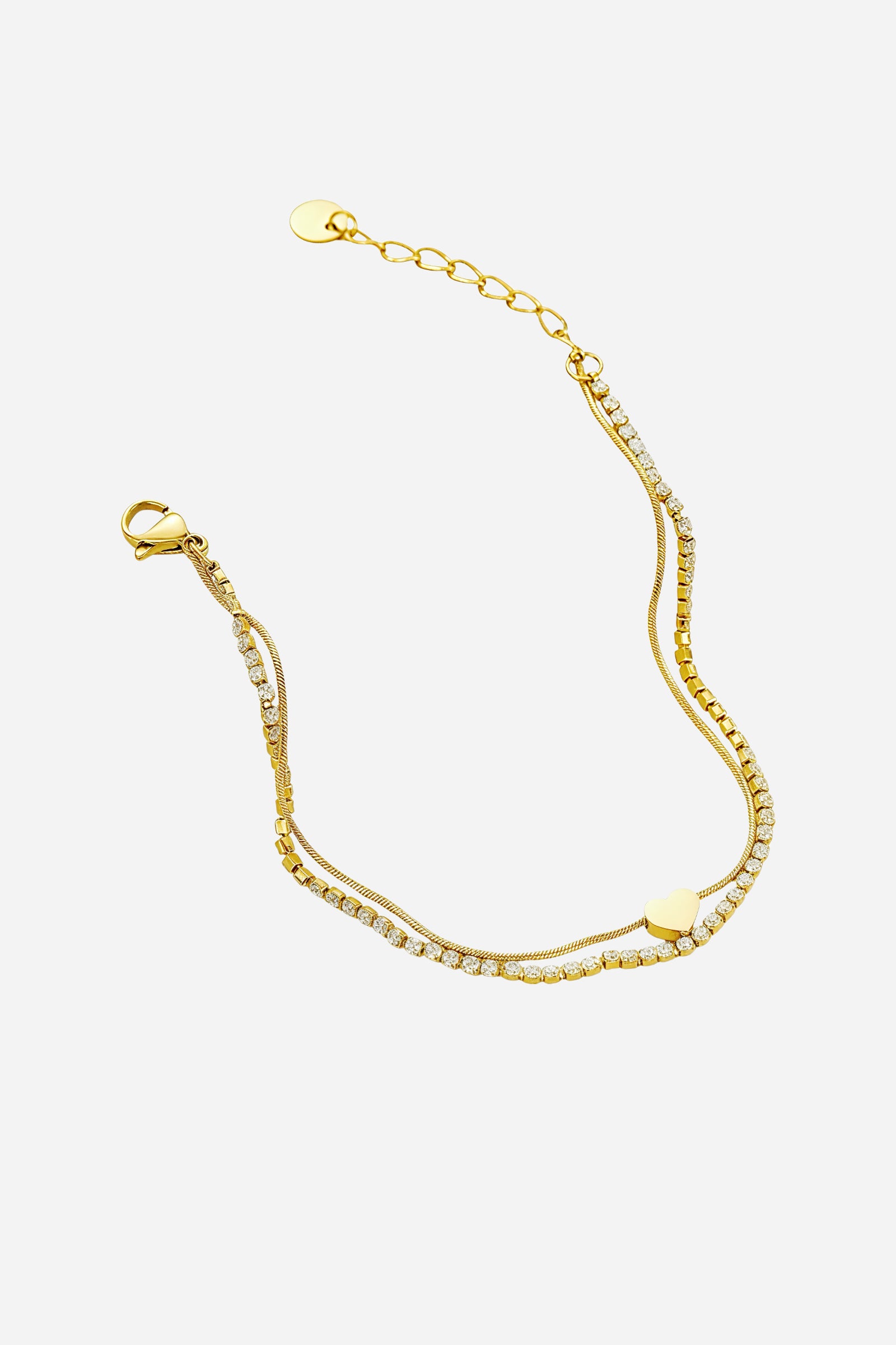 Top-view of GLISTIA’s dual chain gold bracelet featuring a polished heart charm and sparkling tennis stones.