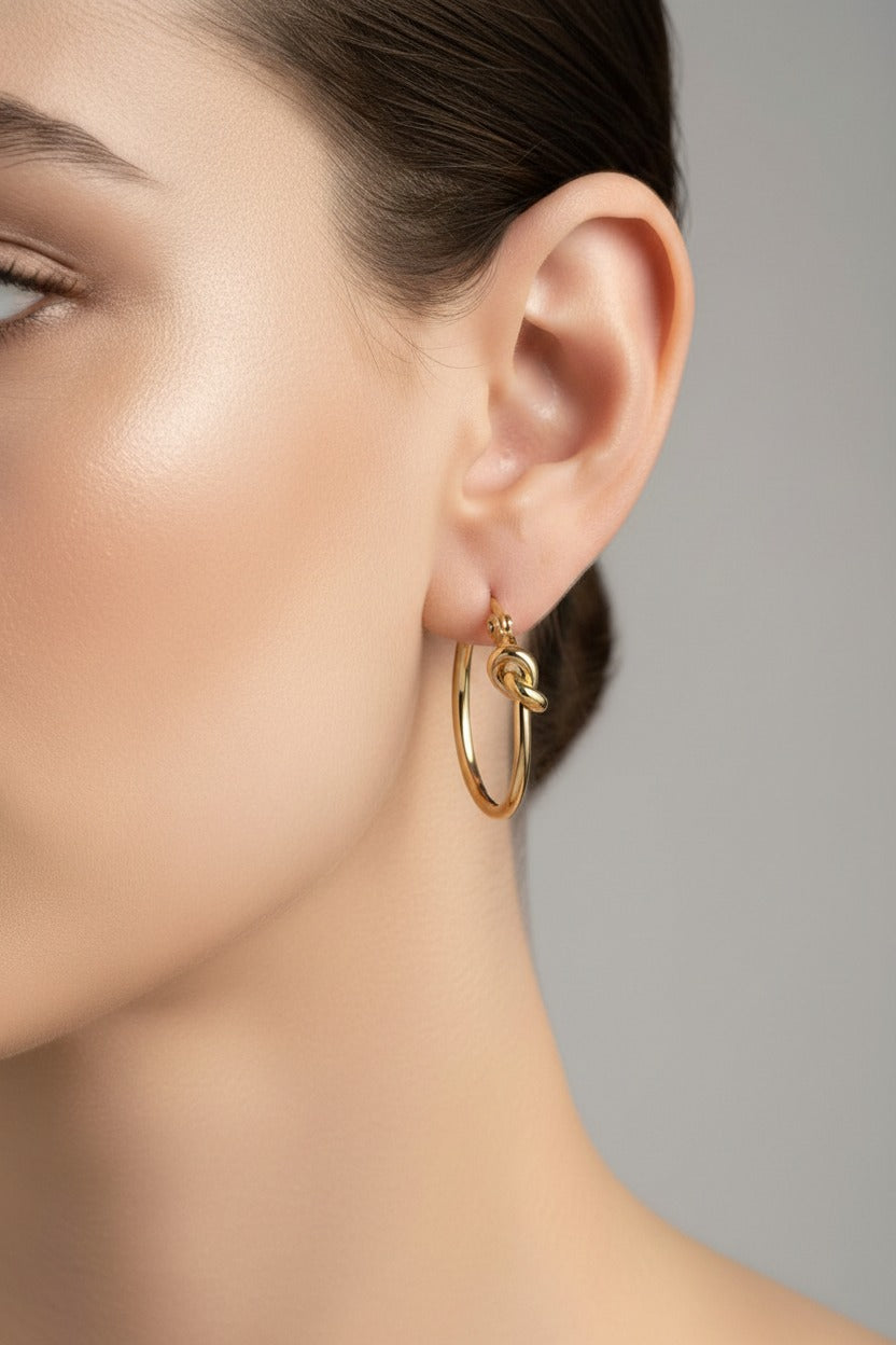 Knot hoop earrings crafted from stainless steel with 18K PVD gold plating, featuring a classic hoop design with a polished knot detail