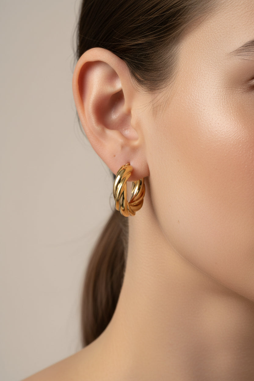 Close-up of large twisted hoop earrings in 18K PVD gold plated stainless steel, showcasing a sculptural rope-inspired texture