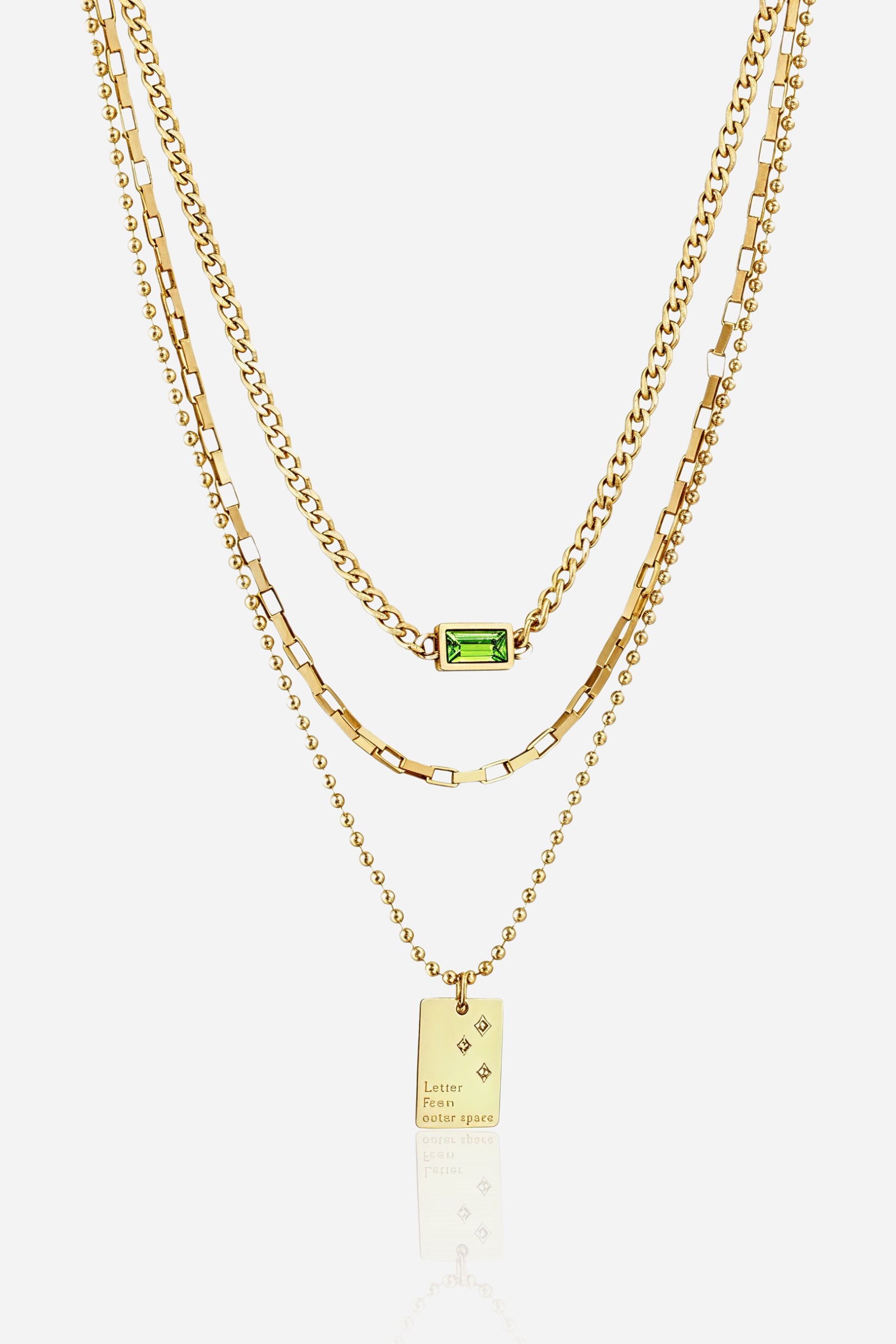 Front view of GLISTIA Luna Verde Layered Necklace with gold chains, green baguette gemstone, and engraved charm.