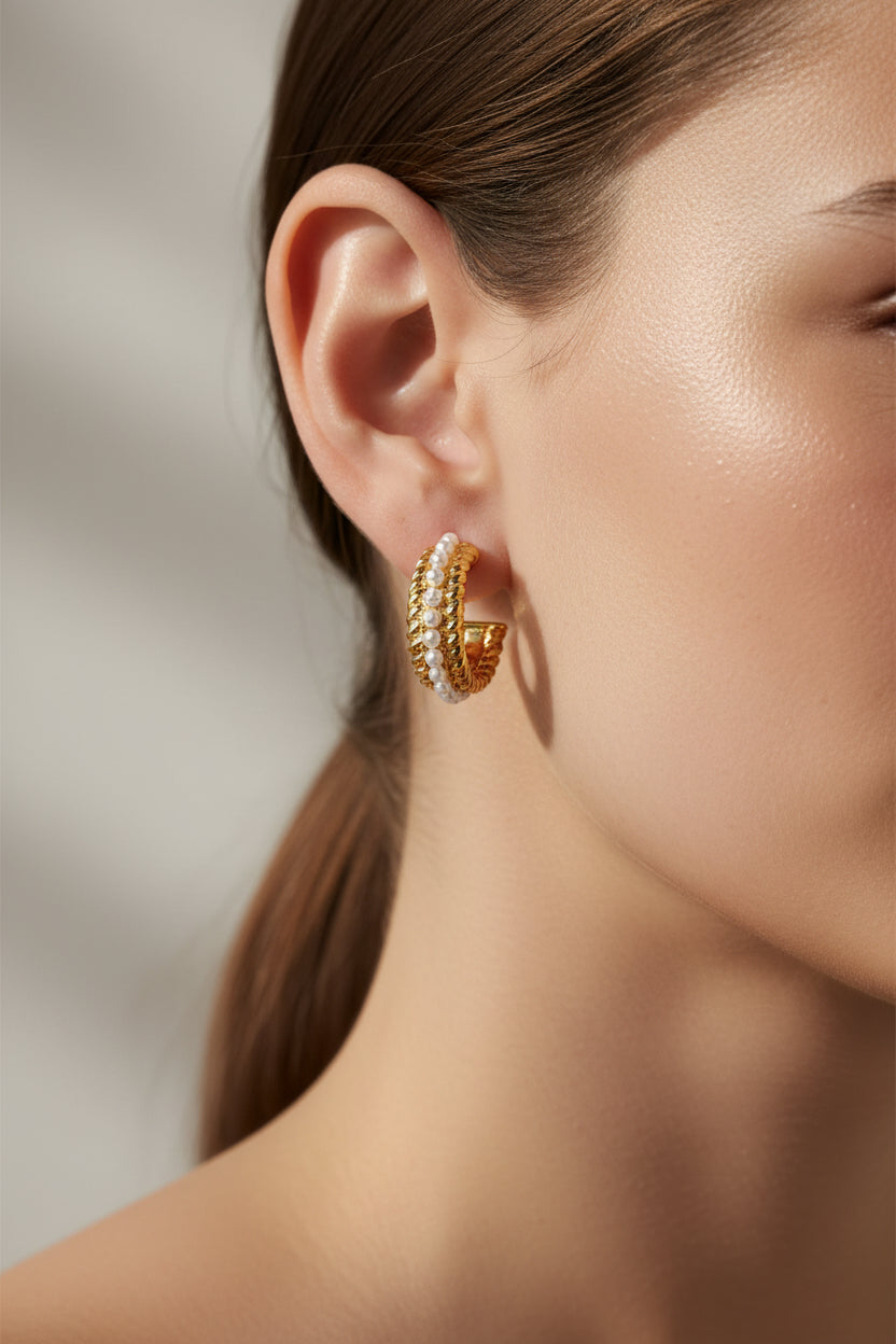 Close-up of textured C-hoop earrings in 18K PVD gold plated stainless steel, showcasing twisted rope design with luminous imitation pearl detailing