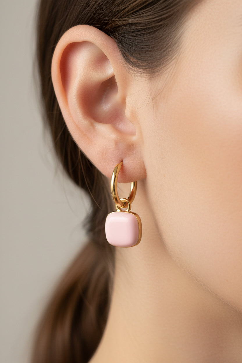 Model wearing pink charm drop hoop earrings crafted from 18K PVD gold plated stainless steel.
