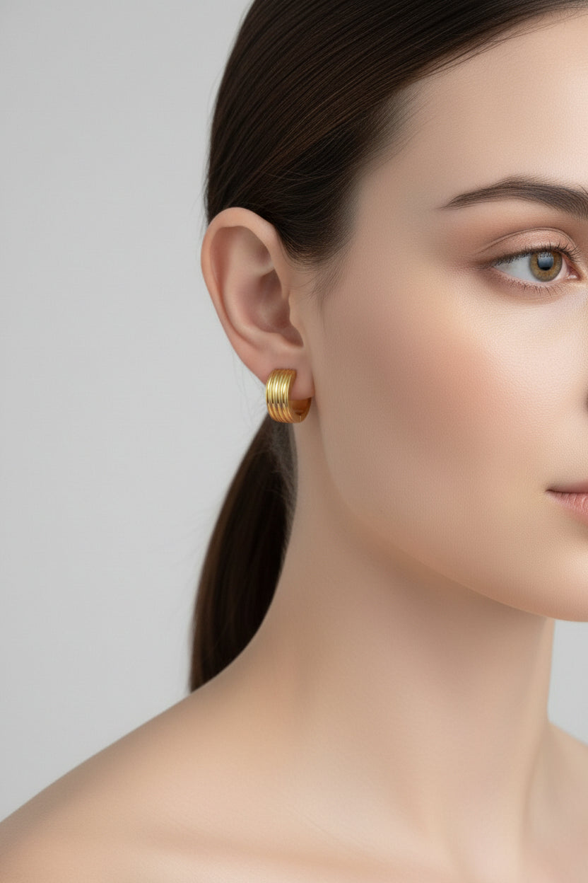 Close-up side profile of ribbed huggie hoop earrings in 18K PVD gold plated stainless steel.