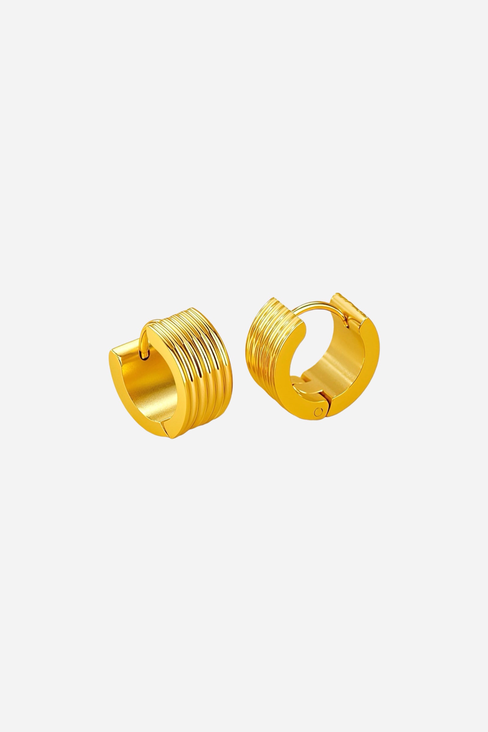 Close-up of ribbed huggie hoop earrings crafted from high-quality stainless steel, featuring a sleek PVD 18K gold-plated finish with vertical grooves and a smooth hinged closure – GLISTIA.