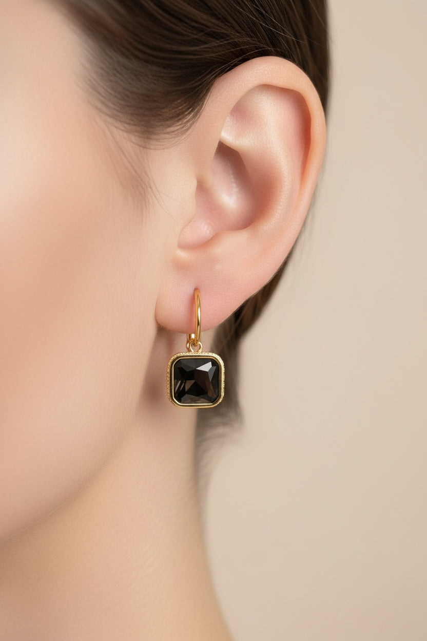 Square black crystal drop earrings by GLISTIA crafted from stainless steel with 18K PVD gold plating, featuring a faceted black crystal and lever back closure.