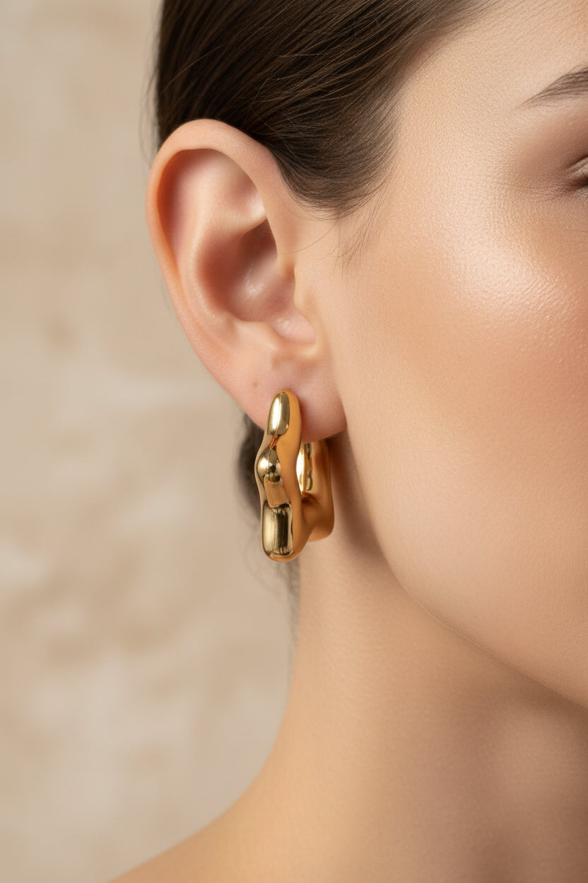 Stellar gold hoop earrings shown in side view, crafted from stainless steel with 18K PVD gold plating and sculptural star inspired curves.
