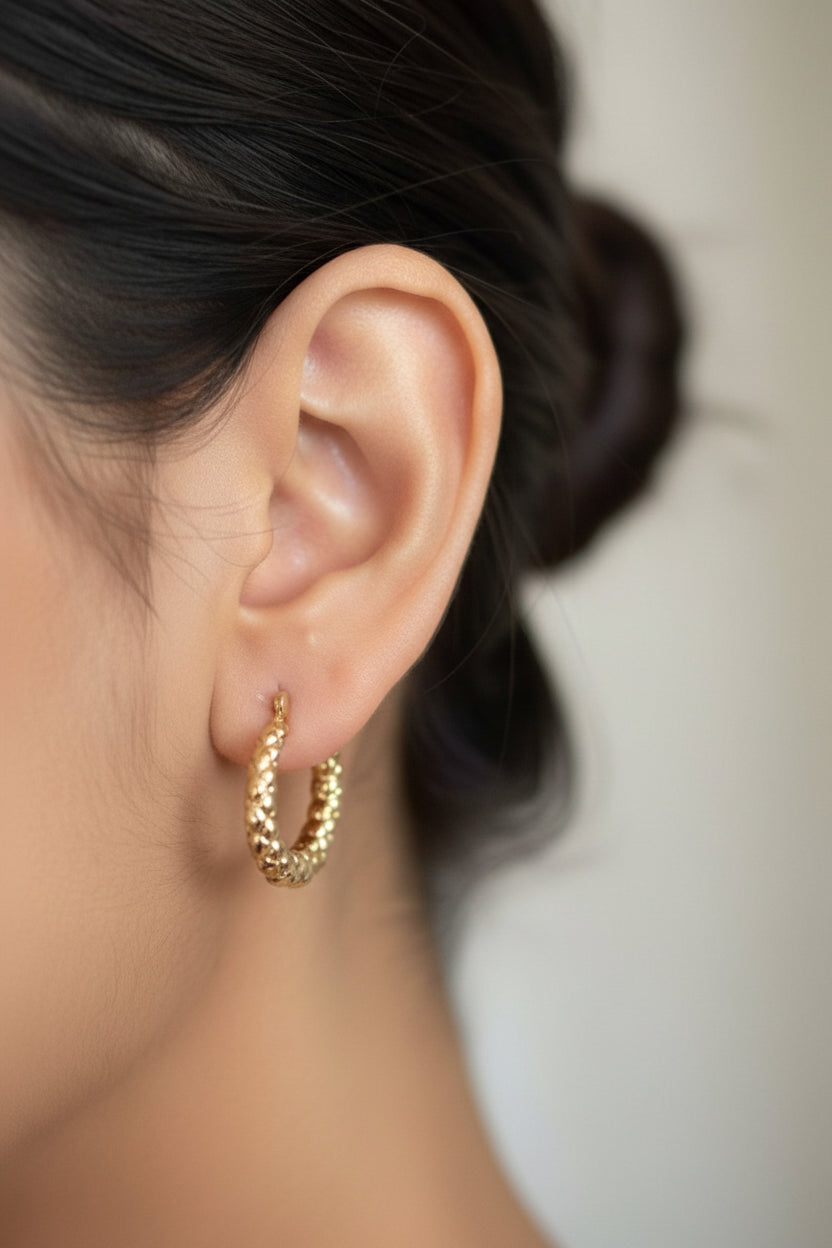 Close-up view of textured dome hoop earrings crafted from stainless steel with 18K PVD gold plating and a detailed textured design
