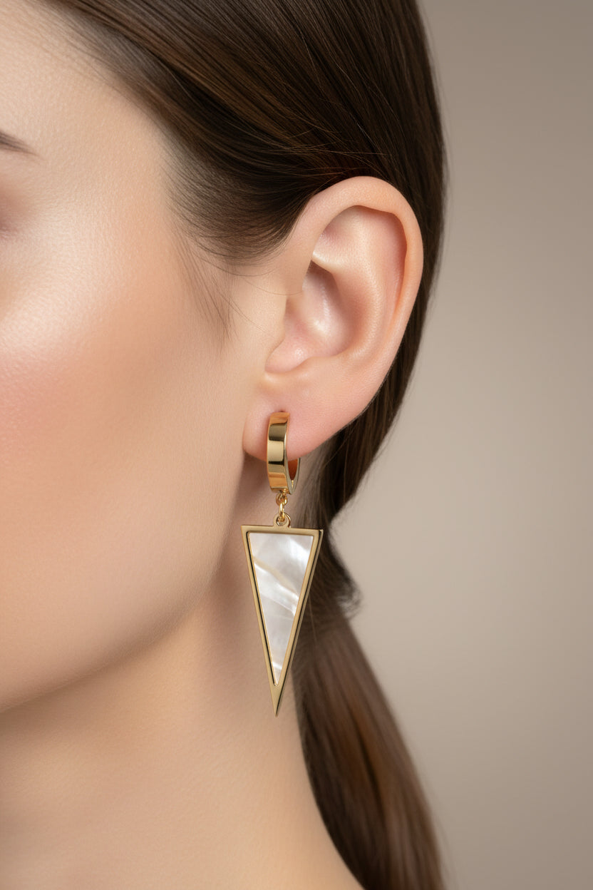 Triangle drop huggie earrings worn on ear in 18K PVD gold plated stainless steel.