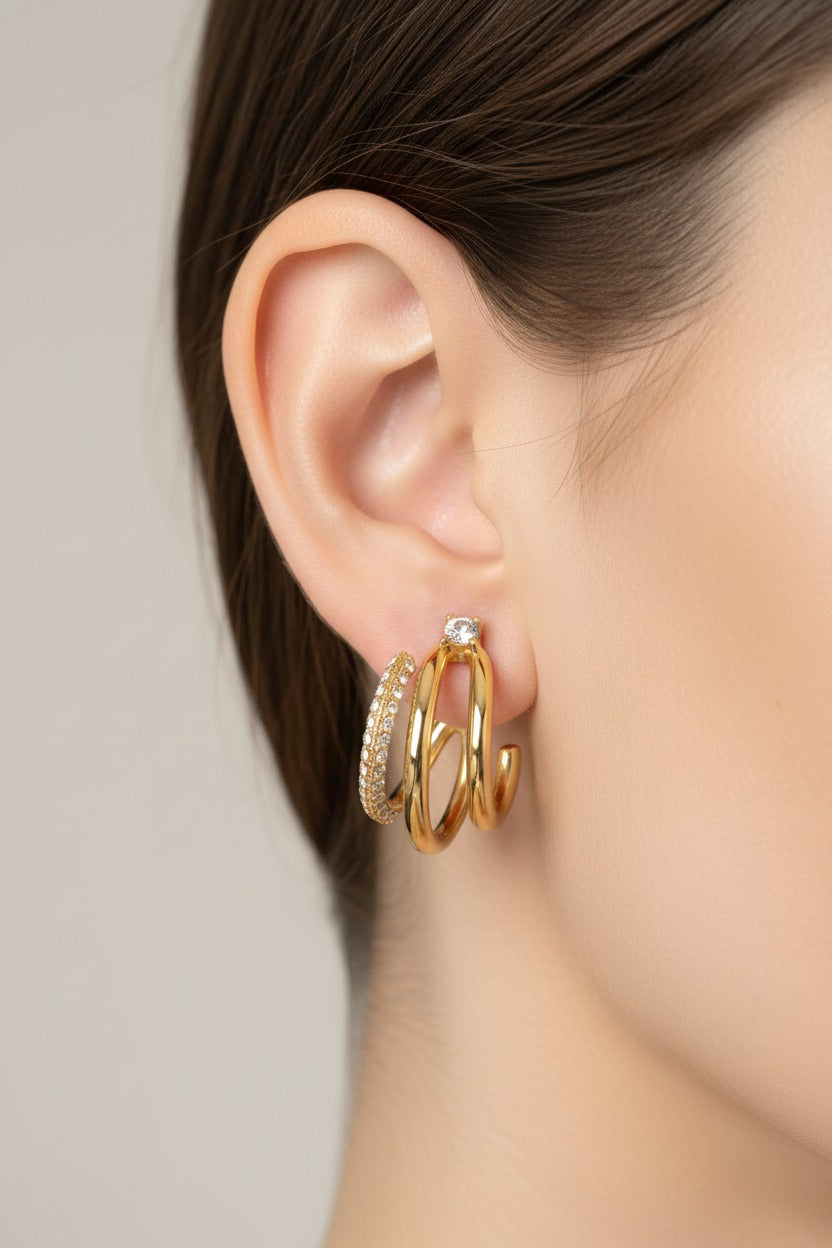 Side view of triple row hoop earrings in 18K PVD gold plated stainless steel with polished gold rows and crystal pavé accents