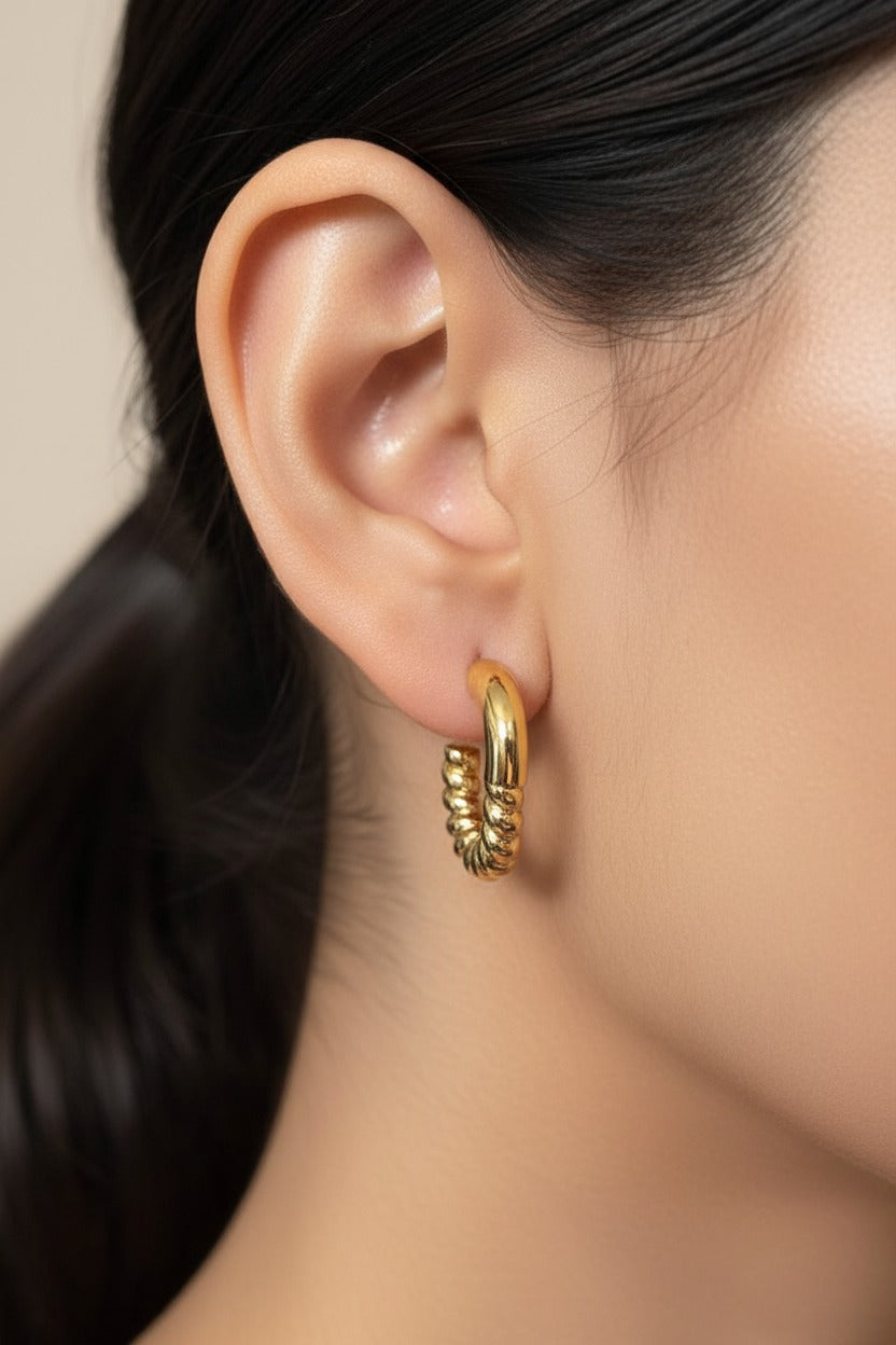 Twisted half hoop earrings in 18K PVD gold plated stainless steel with sculptural twisted detail and polished gold finish