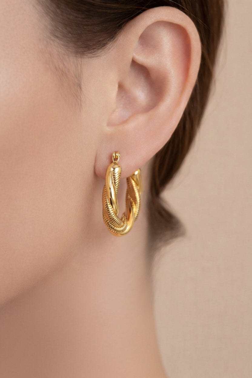 Twisted rope hoop earrings in 18K PVD gold plating worn on ear, featuring textured rope detailing and polished stainless steel finish